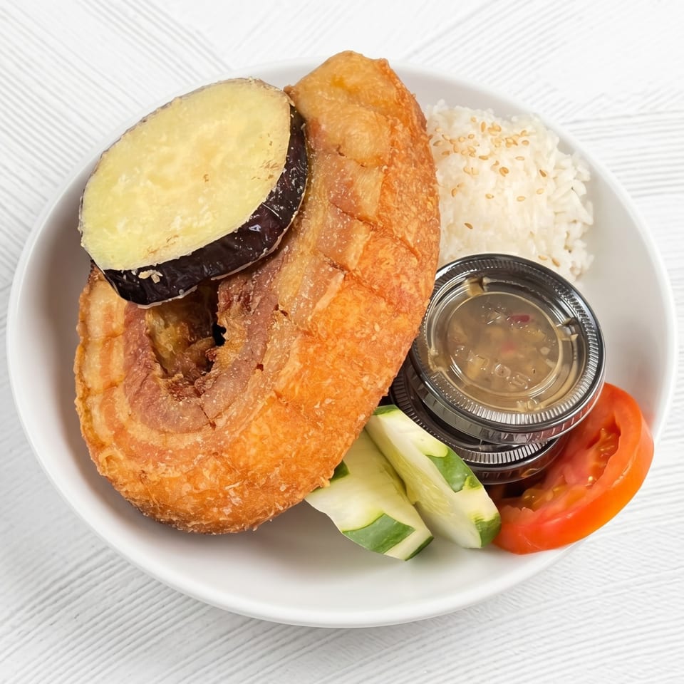 Crispy fried pork belly with rice, sweet potato, cucumber, tomato, and dipping sauce.